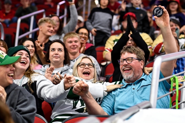 Two fans at an Iowa Wild game cheering after one caught a flying puck.